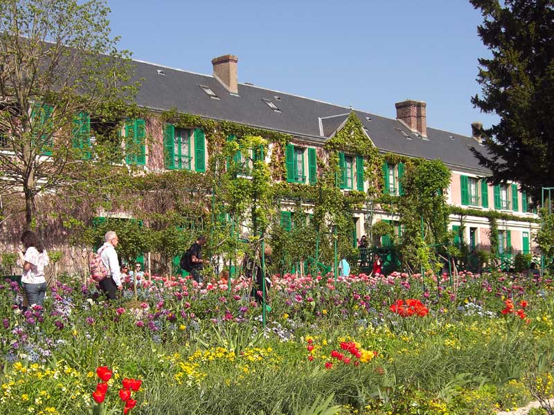 Claude Monet's house at Giverny with its green shutters behind the spring flower garden